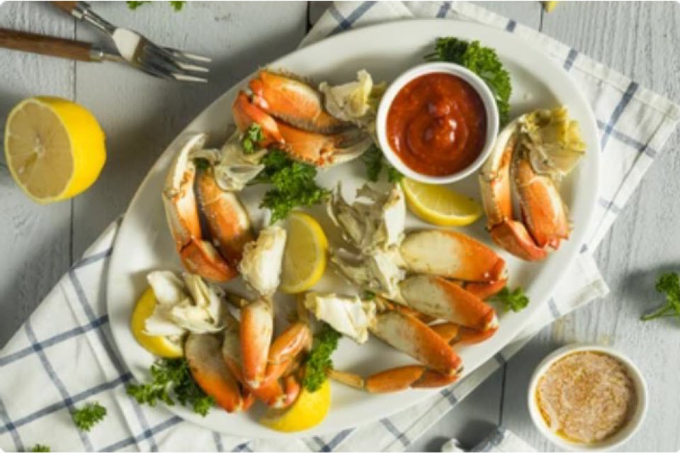 A plate of crab legs with lemon and dipping sauce A plate of crab legs with lemon and dipping sauce